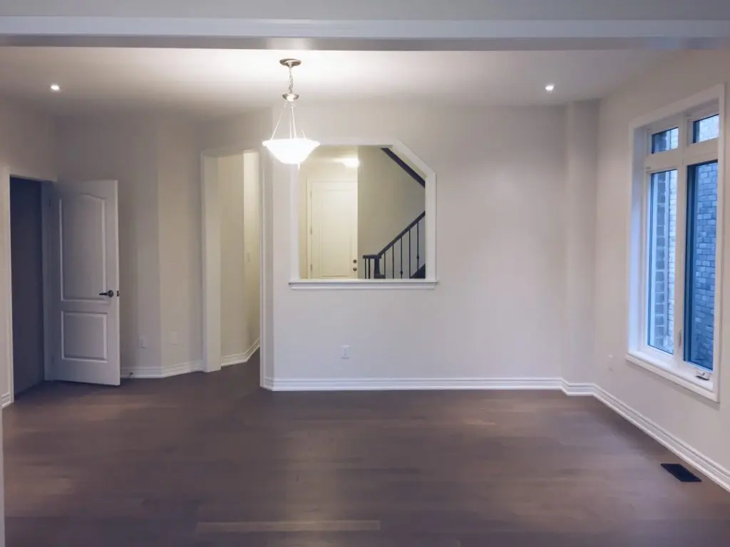 Spacious open-concept living area with smooth off-white walls, dark hardwood floors, and crisp white baseboards, expertly finished by local Painters in Kirkland, WA.