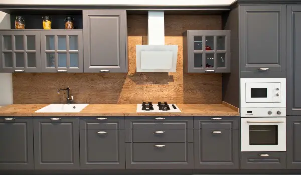 Modern kitchen featuring freshly refinished grey cabinets with clean lines, updated hardware, and a warm wood backsplash for a refined, contemporary look.